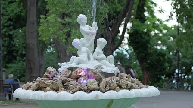 White marble fountain with cherubs in a lush city park