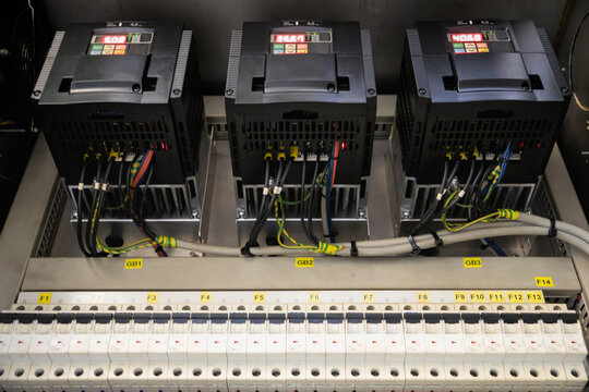 Three variable frequency drives with digital displays mounted over circuit breakers in power cabinet