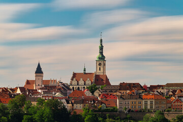 Obraz premium Historic center of Tabor featuring the Church of the Transfiguration and Kotnov Tower above colorful rooftops under a soft long exposure sky in South Bohemia, Czech Republic.