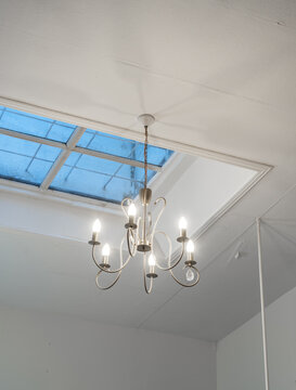 Modern Chandelier Hanging Below Skylight in Minimalist Interior