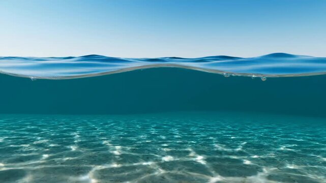 Half underwater, half above water view of clear ocean with blue sky and sandy bottom. Great for nature and travel.