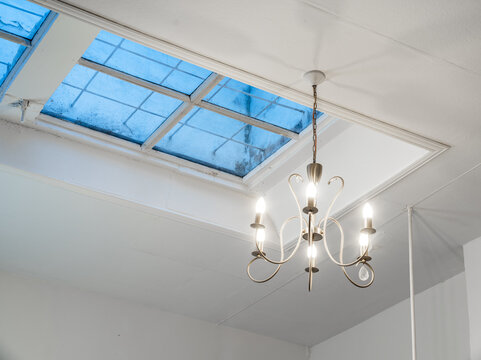 Modern Chandelier Hanging Below Skylight in Minimalist Interior