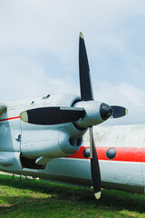 An old airplane propeller stands still in a grassy area under a cloudy sky near a small airfield during the afternoon hours © DSMT