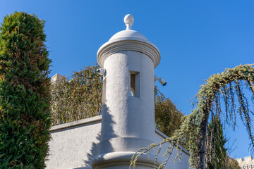 Low-angle shot captures a white stucco turret or decorative pillar topped with a dome and finial. Two security cameras are mounted on its sides © John_Doo78