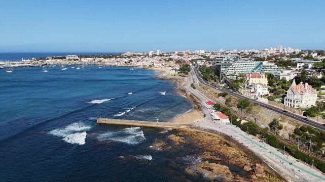 Aerial panoramic drone view of beach breakwater and coastal highway in Cascais Portugal