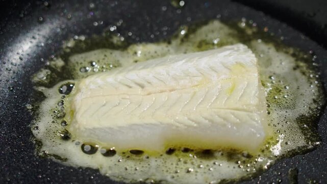 Frying white fish fillets. Frying hake fillets in a hot pan Kitchen permeated by enticing smells of melting butter and cooked fish. Cozy culinary space filled with inviting scents