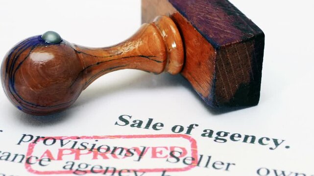 Approved Stamp on Sale of Agency Document With Wooden Stamp Close-Up Business Agreement