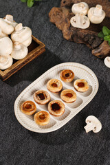 Fototapeta premium Sautéed White Mushrooms with Fresh Wild Mushroom Produce on Dark Slate Kitchen Background