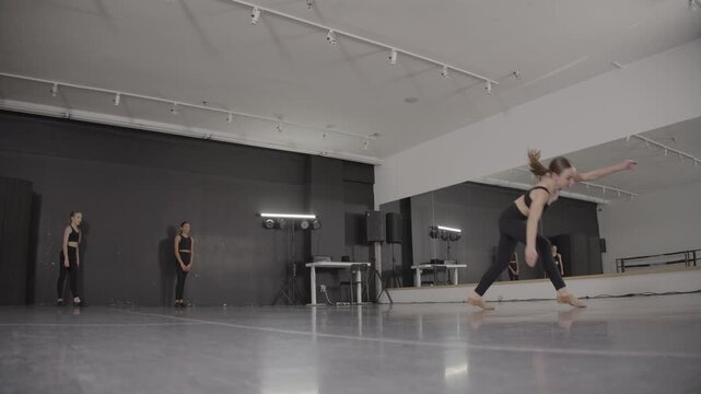 Acrobatic young female ballet dancers training in a modern dance studio
