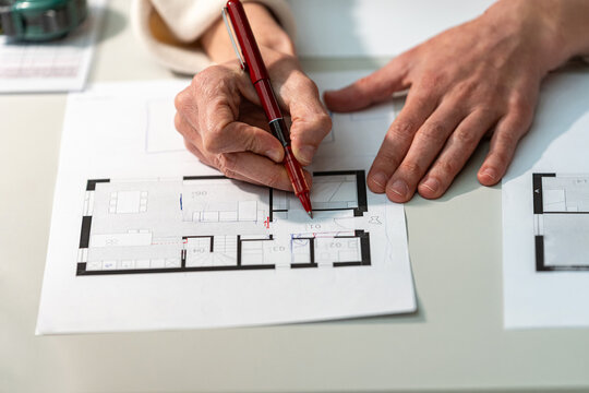 Architect hands drafting floor plan with red pen