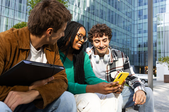 University students sharing smartphone content outdoors in urban setting