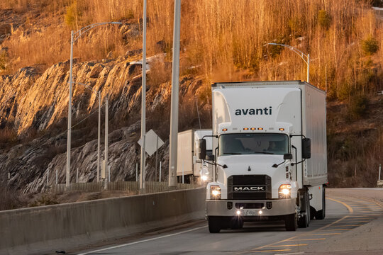 Quebec, Canada, 24 April 2026 : A white Avanti semi-truck, a Mack model, drives on a highway with rocky hills in the background.