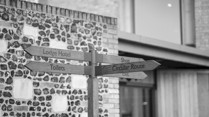 Wooden directional signpost pointing to hotel shop toilet and circular route © Preethiloki