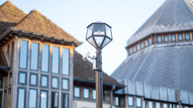 Street lamp post with security camera in front of historic building exterior