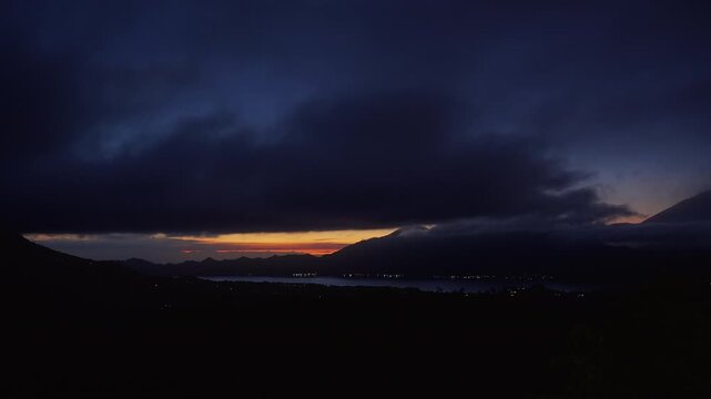Dramatic Dawn Over Mount Abang and Lake Batur Beneath Massive Storm Clouds, Panoramic Volcanic Landscape With Glowing Horizon and Peaceful Highland Atmosphere