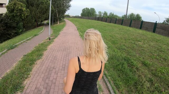 female in exercise clothing is running in a park, demonstrating a healthy lifestyle. Fit woman jogging on a rural road, representing a healthy life. female doing a cardio jogging workout outdoors.