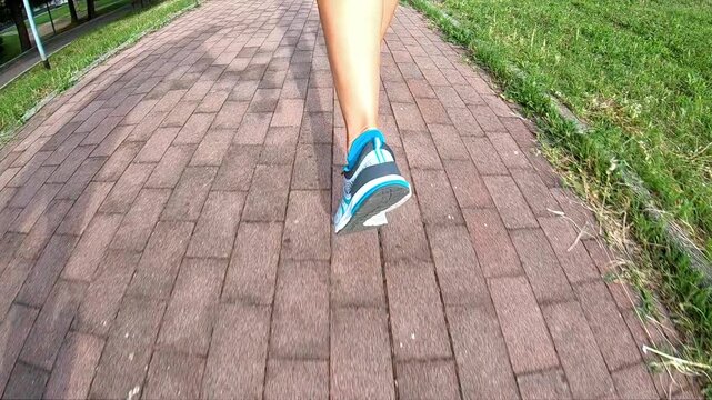 Footwear for exercise in slow motion being used in the park at sunset, viewed from behind while running along a rural road. SLOW MOTION