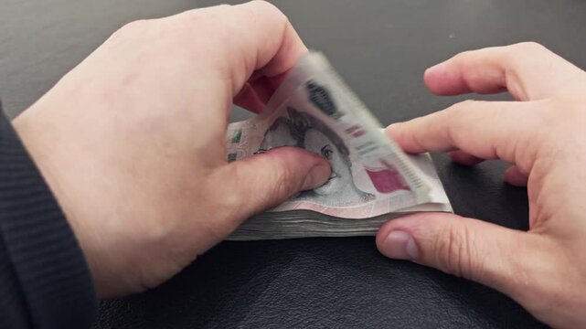 Person counting a wad of argentine peso banknotes