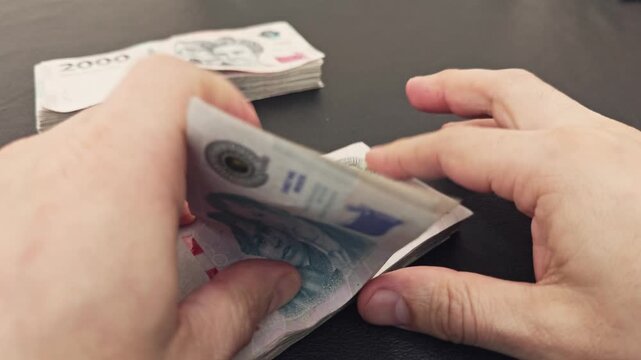 Hands counting argentinian pesos banknotes money