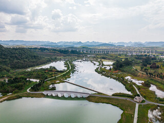 Naklejka premium Tranquil wetland lakes with bridge and distant mountains