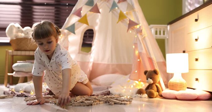 Little girl playing with building blocks in wigwam at home