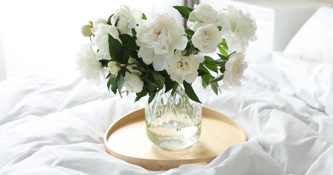 Bouquet of beautiful peony flowers on bed at home