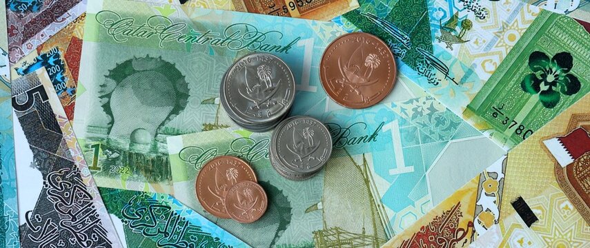Qatari riyal money bills and coins in pile. Big amount of Qatar QAR currency cash close up