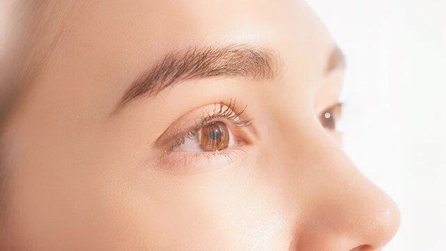 Close up video of a serene face with soft glowing skin and expressive brows in natural light