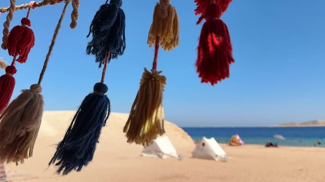 Close Up of Colorful Decorative Tassels on Bedouin Tent with beach camp in the background 