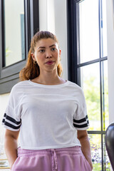 Obraz premium African American woman standing near black-framed window wearing striped tee and pink sweats