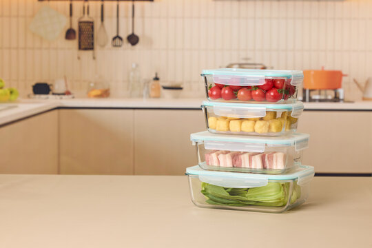 Stacked glass food storage containers with fresh ingredients on kitchen countertop