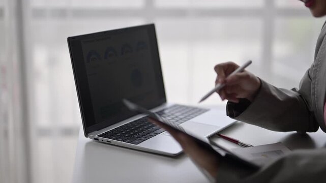 Businesswoman using digital pen presenting business report on laptop