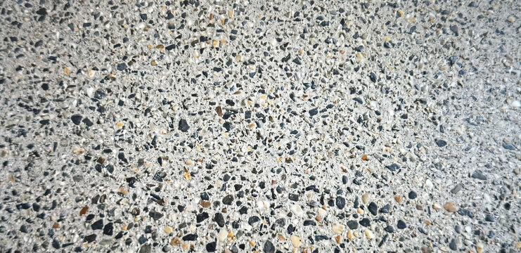 Close-up view of a textured concrete surface featuring various colored aggregate stones embedded within. Ideal for backgrounds and architectural designs.