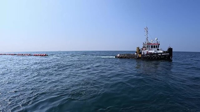 Tugboat repositioning a floating discharge pipeline connected to a cutter suction dredger during offshore dredging operations in the Middle East.