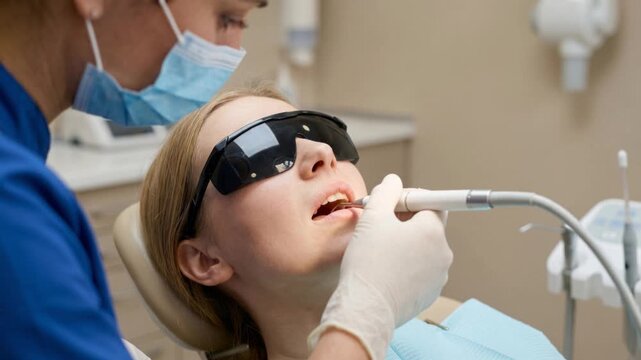 Dentist stomatologist performing professional dental cleaning for young woman, on dental clinic setting, oral hygiene care, healthcare and preventive dentistry concept, 4K video