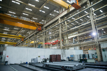 Naklejka premium Large industrial factory workshop interior with overhead cranes and heavy machinery