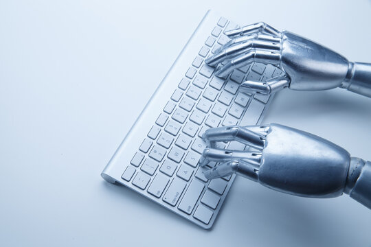 Robotic hands typing on keyboard for artificial intelligence and automation concept