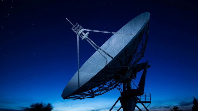 Large satellite dish antenna rotating under starry night sky capturing signals for communication technology