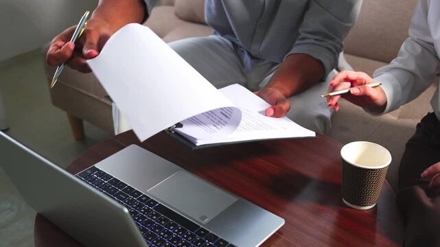  Client pointing at document during business contract signing meeting.Close up of hands reviewing financial insurance contract agreement details.