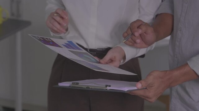  Client pointing at document during business contract signing meeting.Close up of hands reviewing financial insurance contract agreement details.