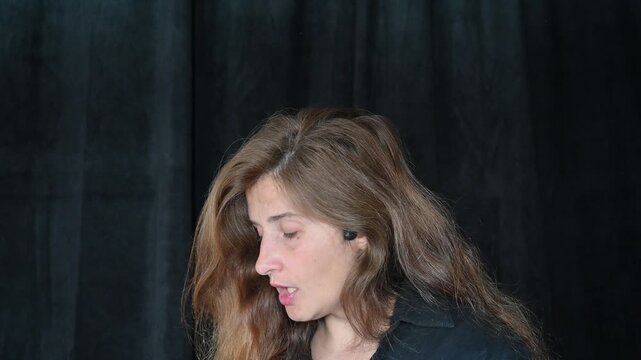 portrait of a woman on a black background
Woman with long hair reading and talking,