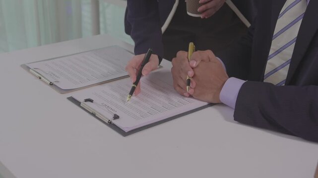 A professional lawyer is discussing contract terms with a client at a law firm. A close-up image of a legal agreement with scales of justice.