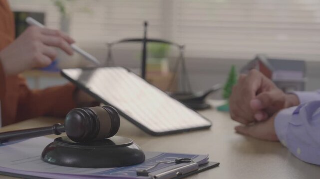 A real estate agent is presenting a digital home purchase agreement to a client on a tablet, along with a house model and concepts related to property law.