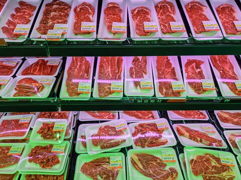Fresh raw beef cuts packaged in trays on display at the supermarket butcher counter