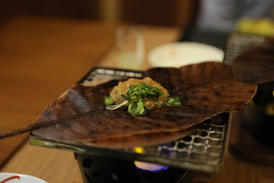 Traditional Japanese hoba miso cooking on a magnolia leaf over flame.
