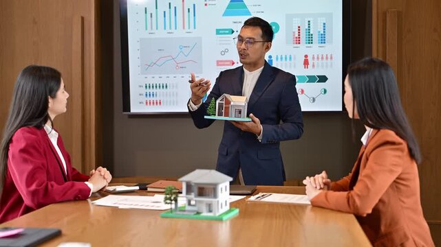 Business presentation with real estate model and data charts in office meeting room