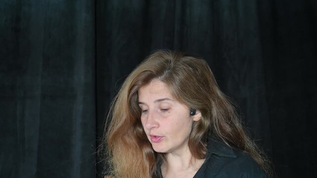 portrait of a woman on a black background
Woman with long hair reading and talking,