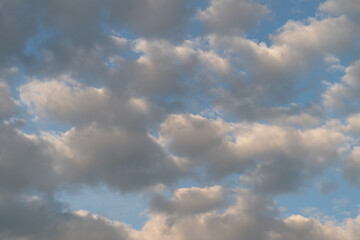 Obraz premium Soft cumulus clouds at golden hour over blue sky