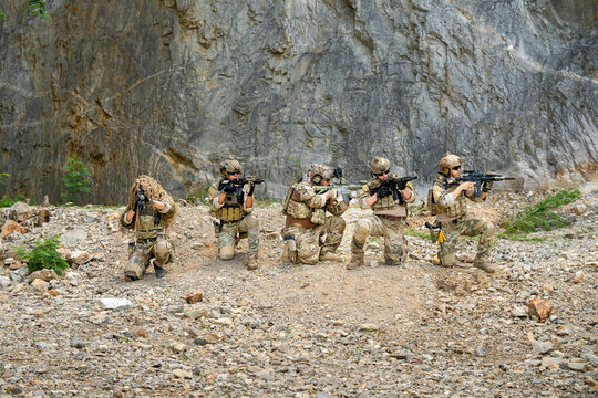 Military training operation rocky terrain action photography outdoor setting ground-level perspective teamwork and strategy