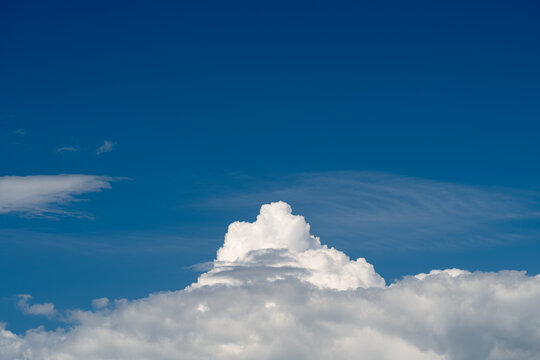 Dramatic white cumulus cloud rising beneath deep blue sky